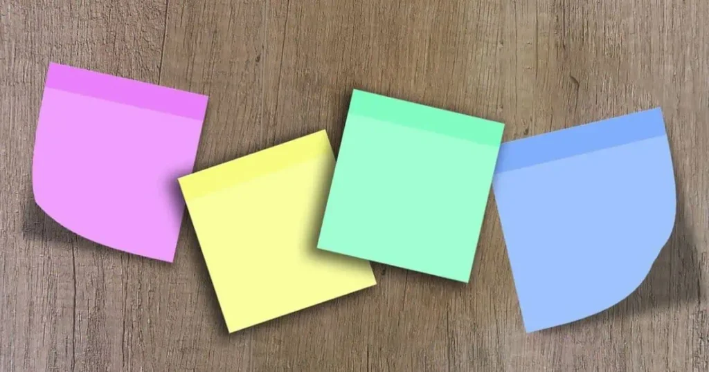 A collection of colorful 6 inches long sticky notes arranged on a rustic wooden table, showcasing various notes and reminders.