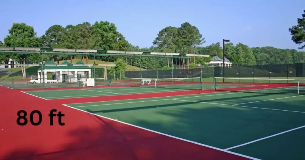 A vibrant tennis court, 80 feet long, featuring a green playing area and red boundary lines, ready for a match.