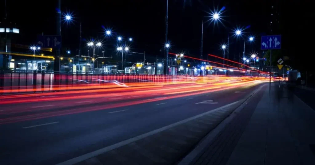 Long exposure photograph capturing a city street at night, showcasing the distance of 5 street lights illuminating the scene.